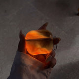 Coque AirPods LUCIØLE Orange — halo phosphorescent dans le noir